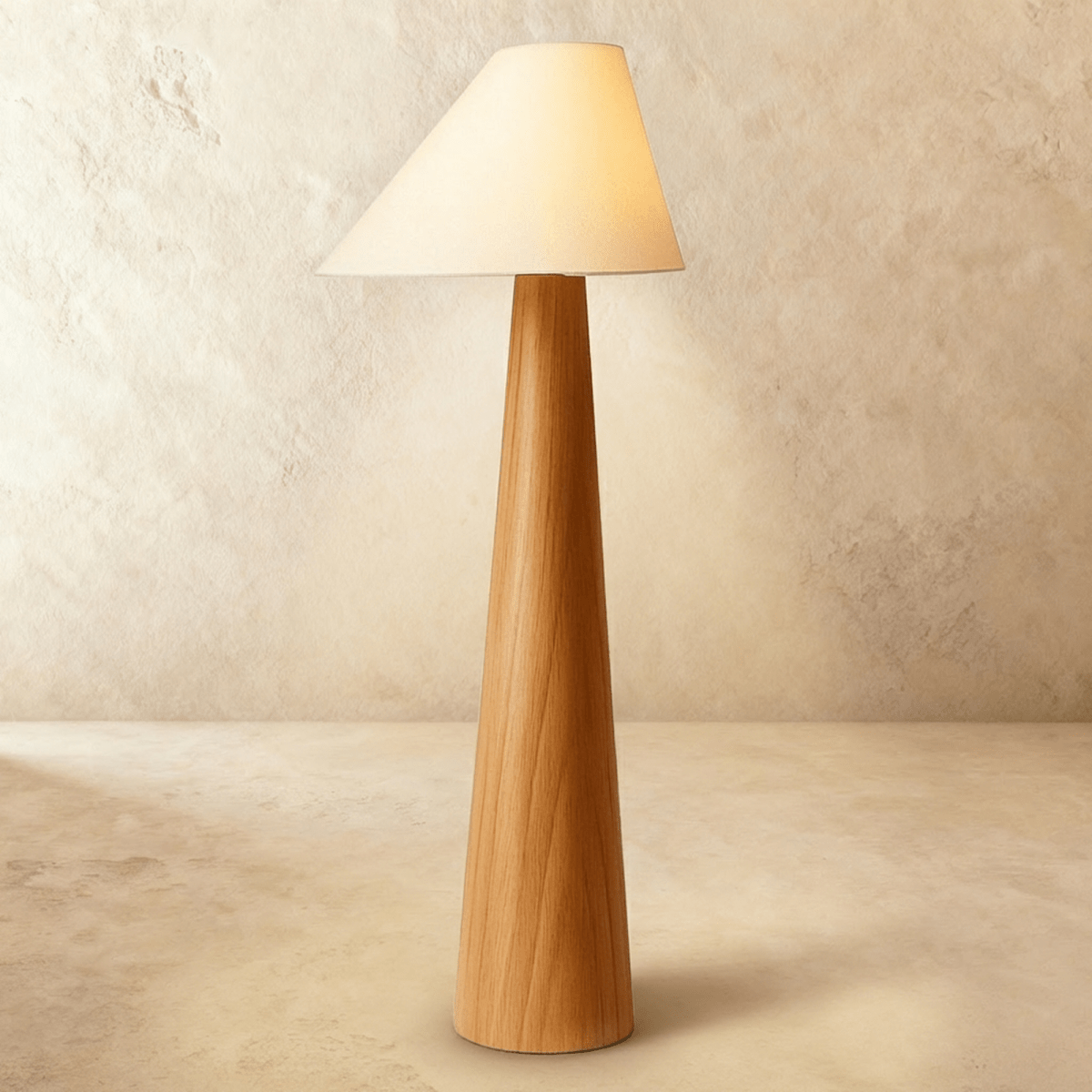 Tall wooden floor lamp with tapered wood base and cream fabric cone shade, lit against white studio background.