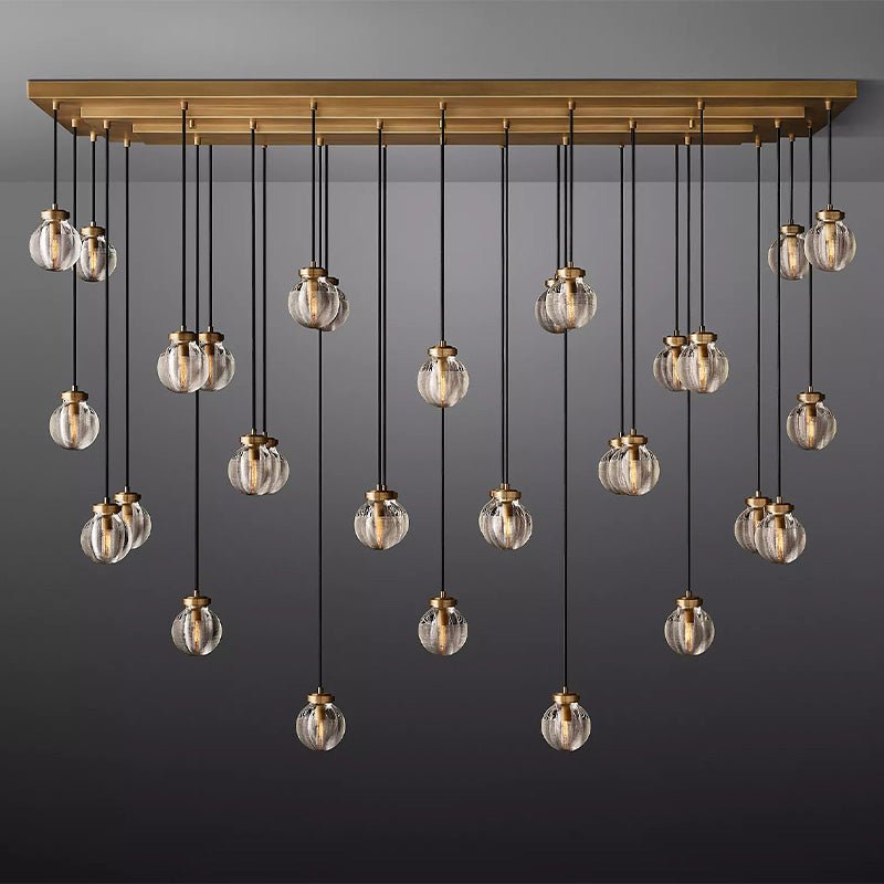 Linear chandelier with brass frame and multiple hanging clear glass globe pendants on gray background.